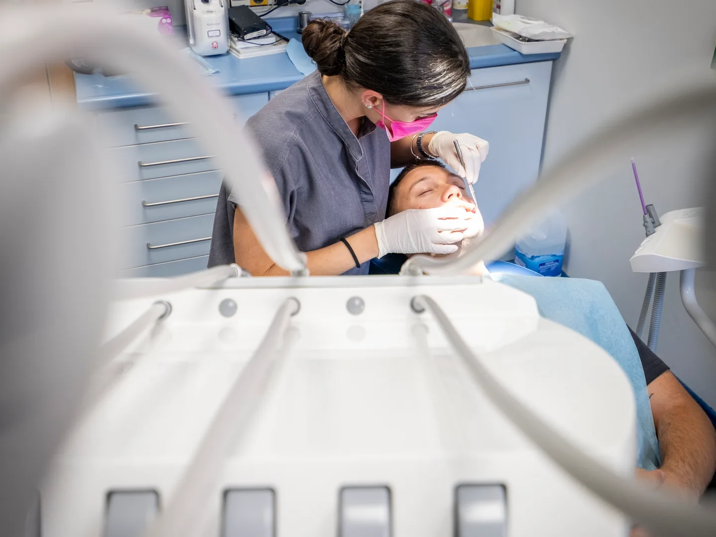 Profesional atendiendo a un paciente vista desde el pie del sillón dental en Lleida