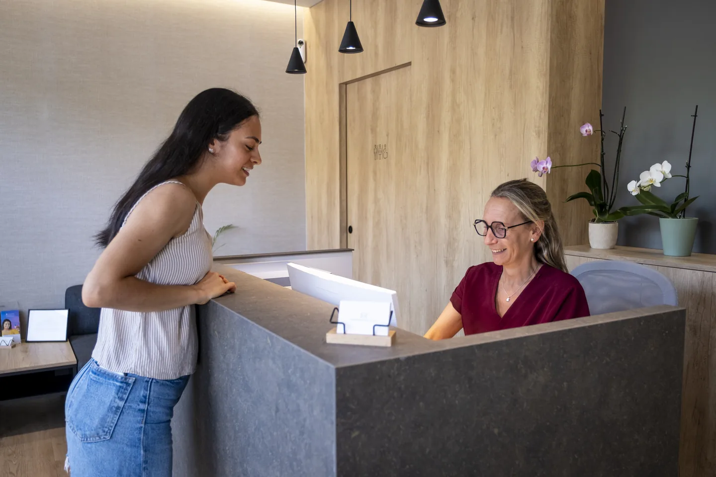 Una paciente hablando con la recepcionista en el mostrador de Tremp