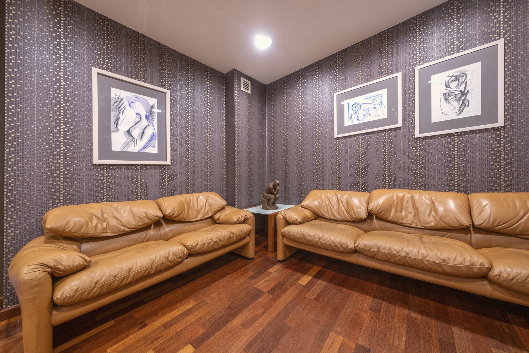 Sala d'espera amb sofàs de pell i obra emmarcada